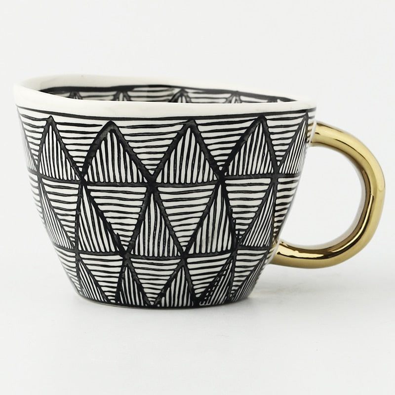 Mugg med abstrakt geometriskt mönster och guldhandtag
