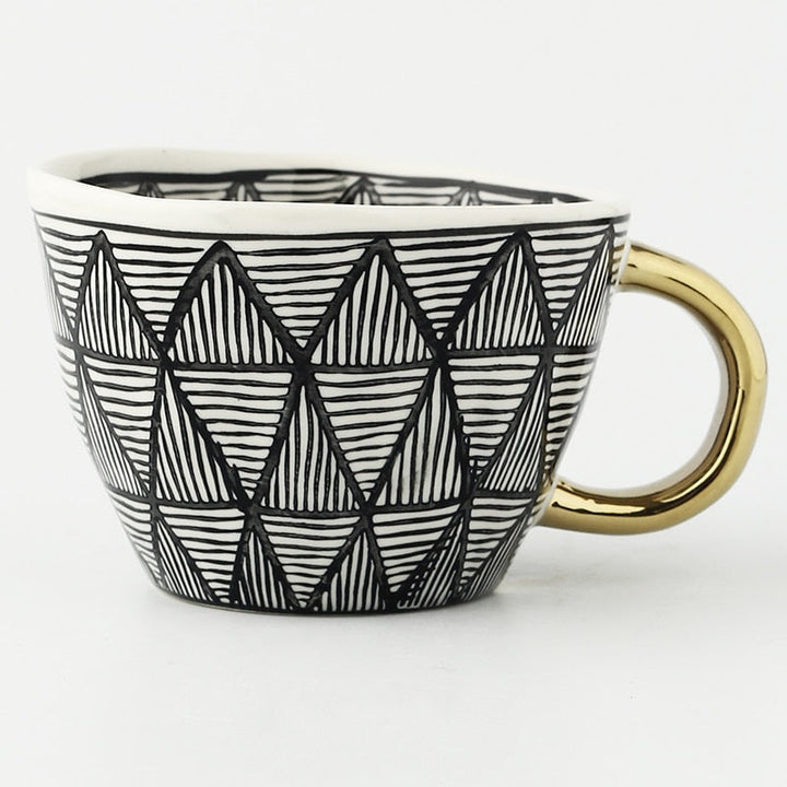 Mugg med abstrakt geometriskt mönster och guldhandtag