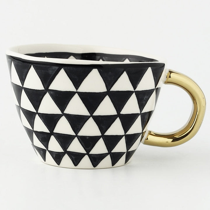 Mugg med abstrakt geometriskt mönster och guldhandtag