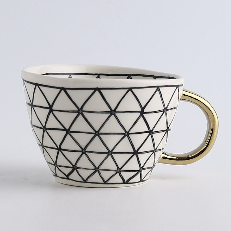 Mugg med abstrakt geometriskt mönster och guldhandtag