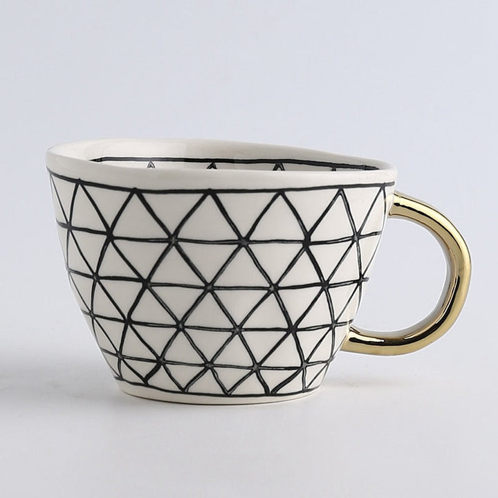 Mugg med abstrakt geometriskt mönster och guldhandtag
