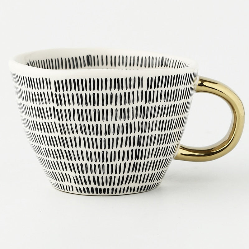 Mugg med abstrakt geometriskt mönster och guldhandtag