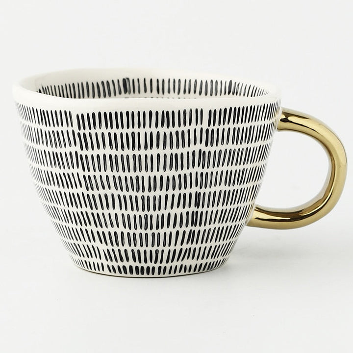 Mugg med abstrakt geometriskt mönster och guldhandtag