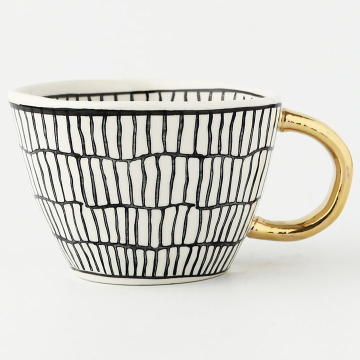 Mugg med abstrakt geometriskt mönster och guldhandtag