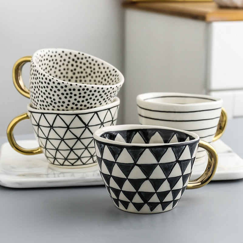 Mugg med abstrakt geometriskt mönster och guldhandtag