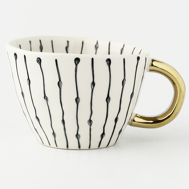 Mugg med abstrakt geometriskt mönster och guldhandtag