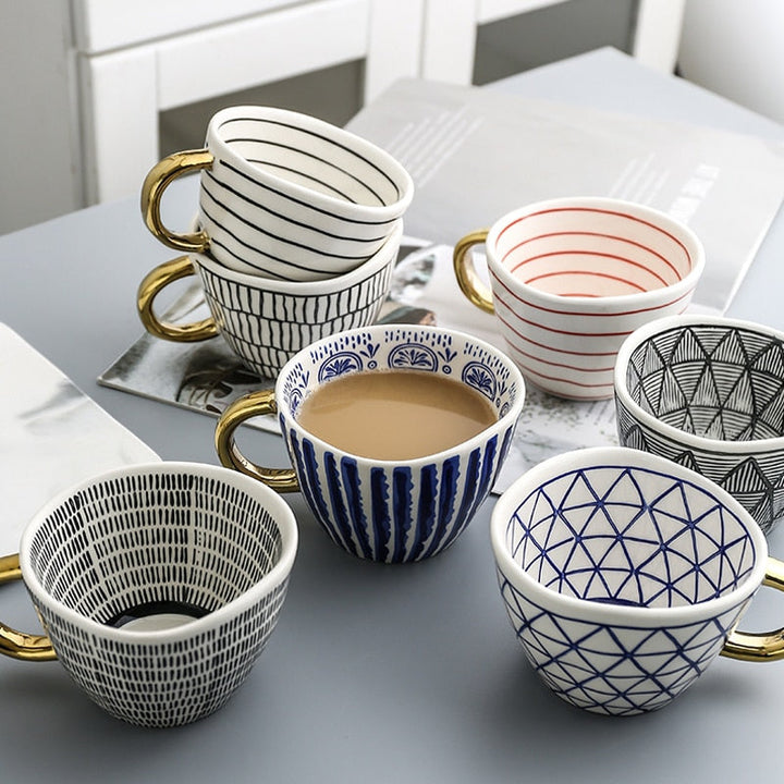 Mugg med abstrakt geometriskt mönster och guldhandtag