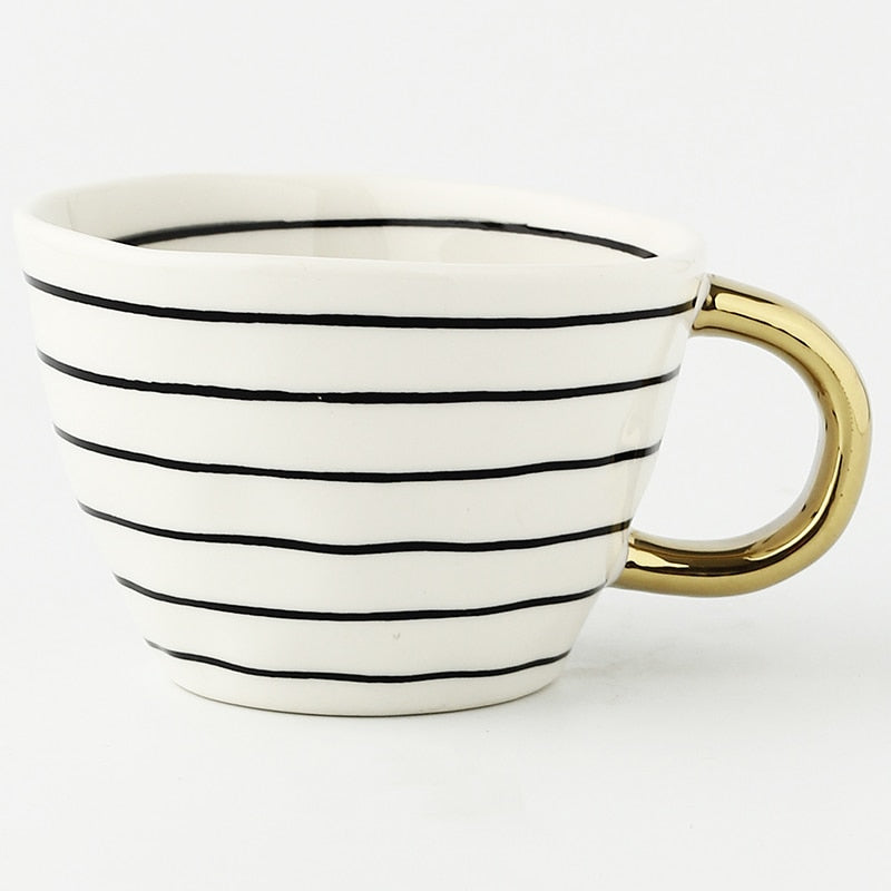 Mugg med abstrakt geometriskt mönster och guldhandtag