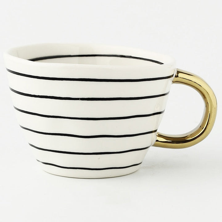 Mugg med abstrakt geometriskt mönster och guldhandtag