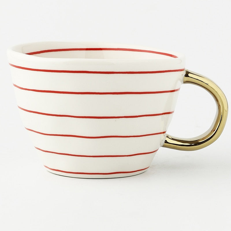 Mugg med abstrakt geometriskt mönster och guldhandtag