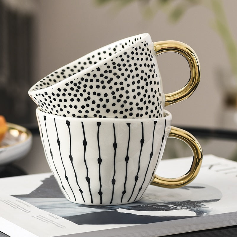 Mugg med abstrakt geometriskt mönster och guldhandtag