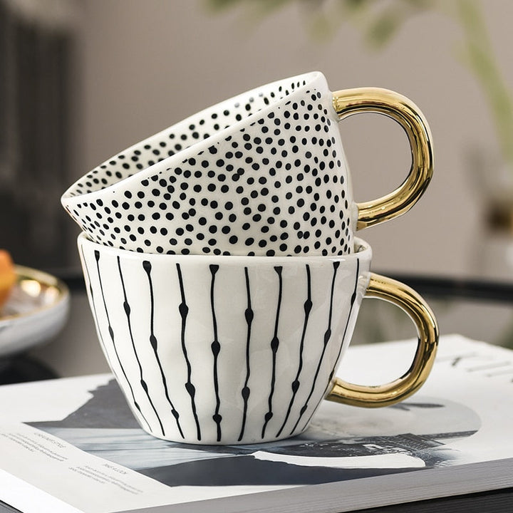 Mugg med abstrakt geometriskt mönster och guldhandtag