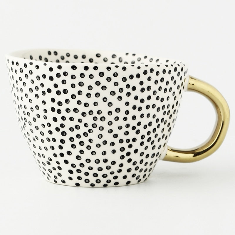 Mugg med abstrakt geometriskt mönster och guldhandtag