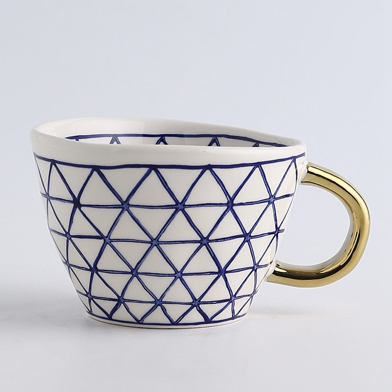 Mugg med abstrakt geometriskt mönster och guldhandtag