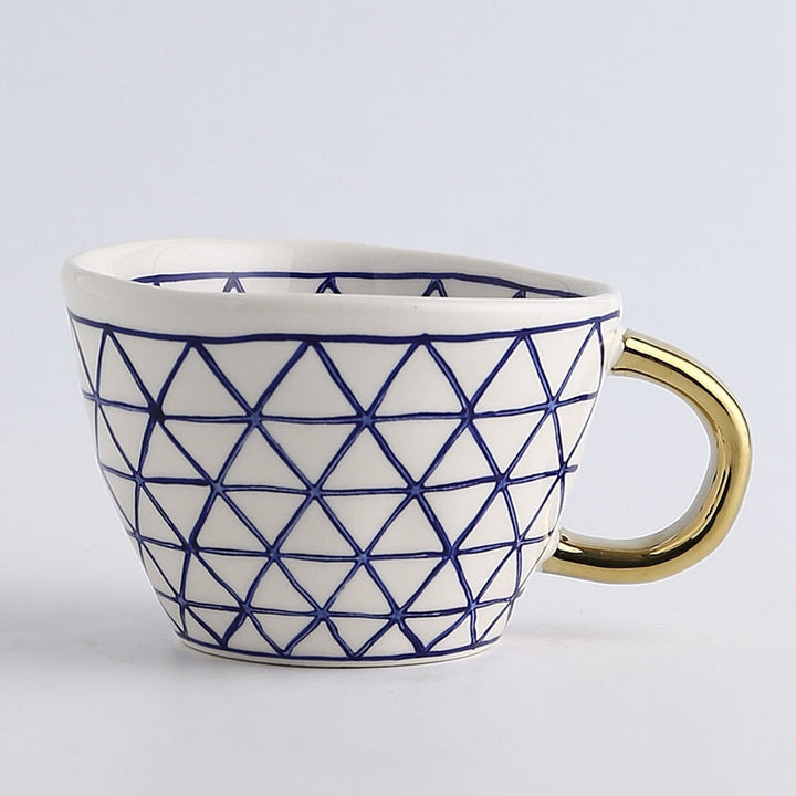 Mugg med abstrakt geometriskt mönster och guldhandtag