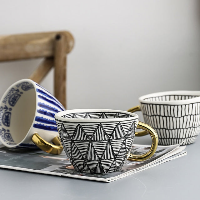 Mugg med abstrakt geometriskt mönster och guldhandtag