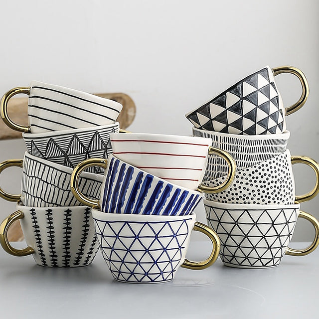 Mugg med abstrakt geometriskt mönster och guldhandtag